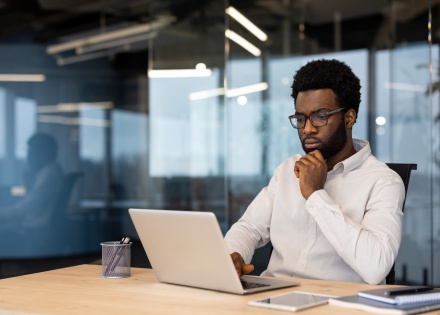 Businessman sitting at a desk calculating payroll taxes in Guinea