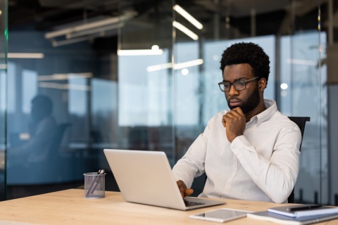 Businessman sitting at a desk calculating payroll taxes in Guinea