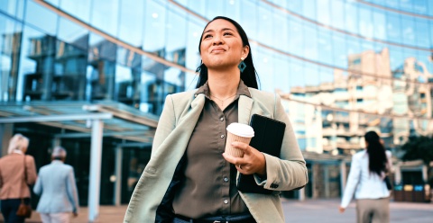 Confident businesswoman walking with coffee outside of a work building