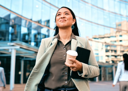 Confident businesswoman walking with coffee outside of a work building