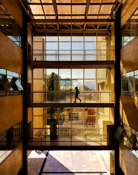 Vista panorámica de un empleado cruzando un puente en el segundo nivel de un edificio de oficinas.