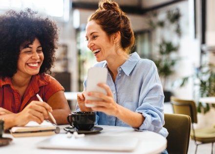 Happy female colleagues reading a text message on a smartphone