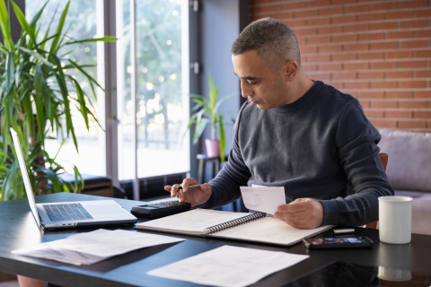 Man using a calculator while reviewing payroll taxes in the Cayman Islands
