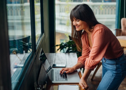 Woman working on laptop on cafe high table