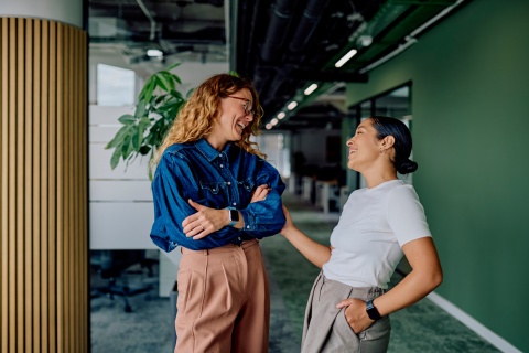 Two women colleagues laughing and talking about workplace culture in Ghana