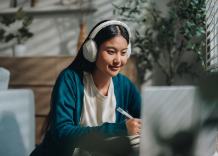 Woman wearing headphones holding a pen in the office