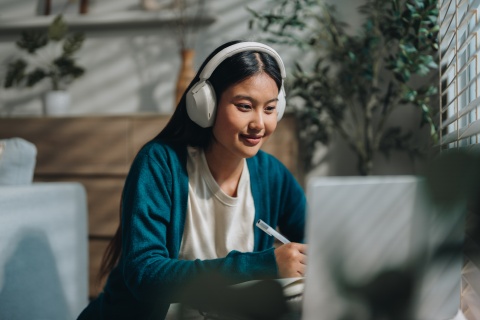 Woman wearing headphones holding a pen in the office